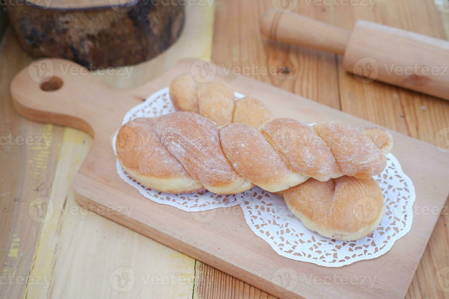 Bread donuts on the wooden table with wooden rolling pin. photo