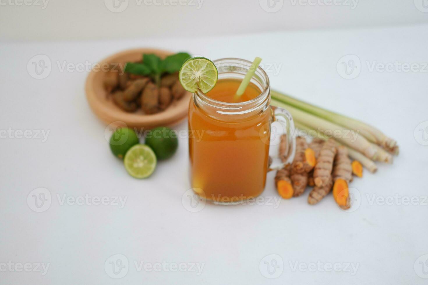 Fresh ginger and lemon juice in a glass jar with ginger roots on white background. photo