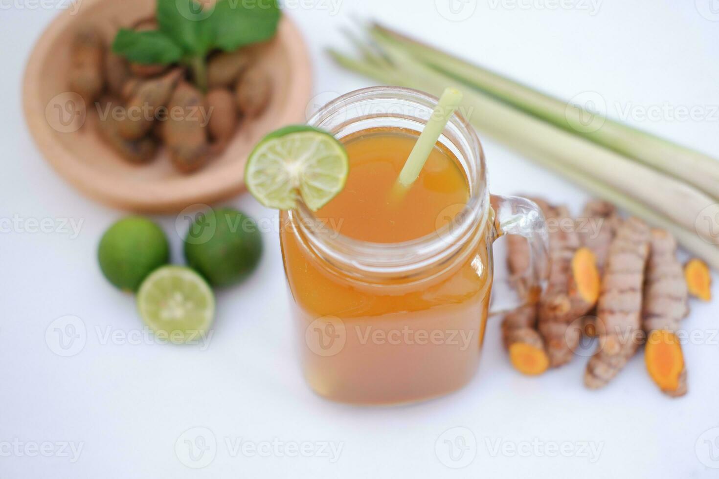 Fresh ginger and lemon juice in a glass jar with ginger roots on white background. photo
