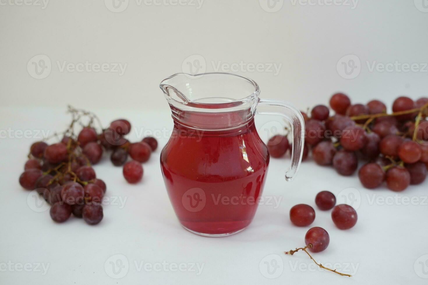 Grape juice in a glass jug with fresh grapes on a white background photo