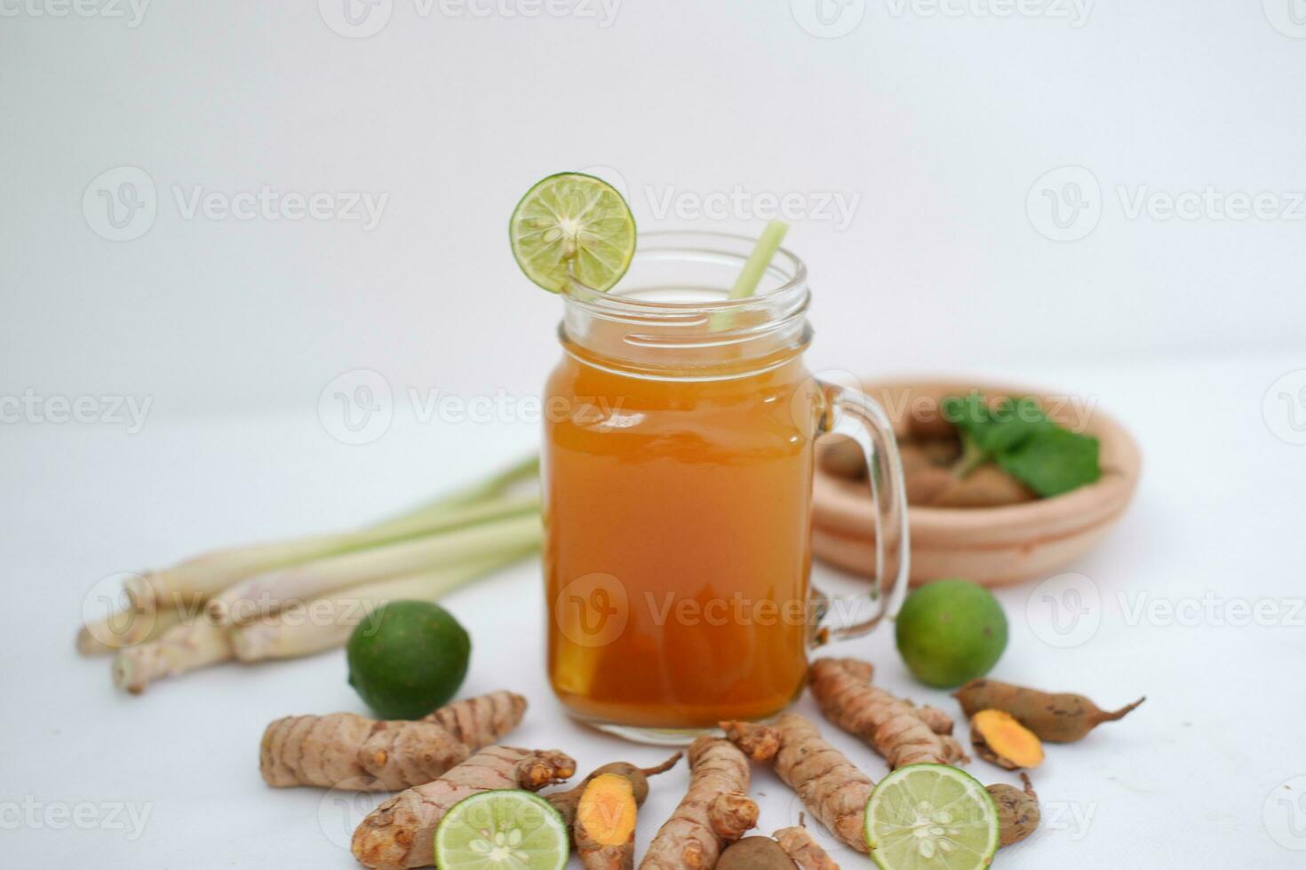 Fresh ginger and lemon juice in a glass jar with ginger roots on white background. photo