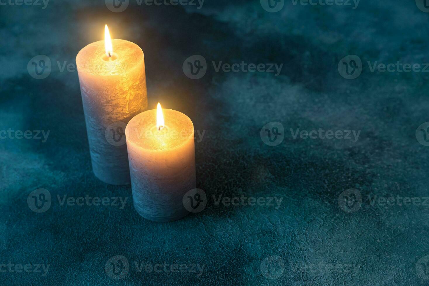 Two burning candles on navy blue background photo