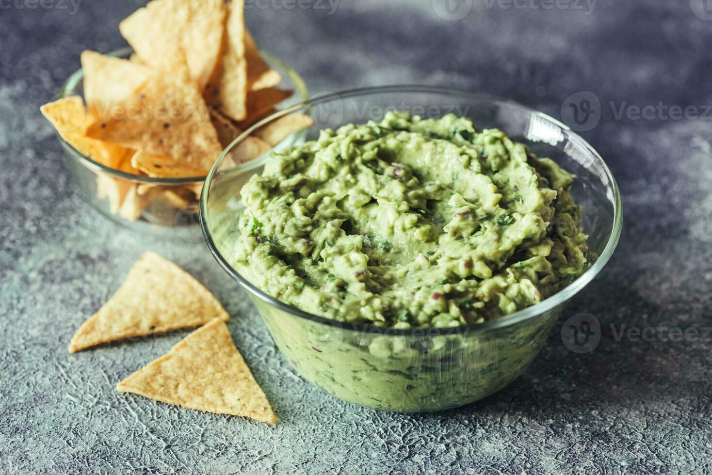 Guacamole in the glass bowl with tortilla chips photo