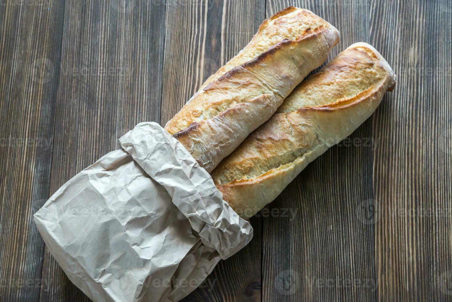 Two baguettes on the wooden background photo