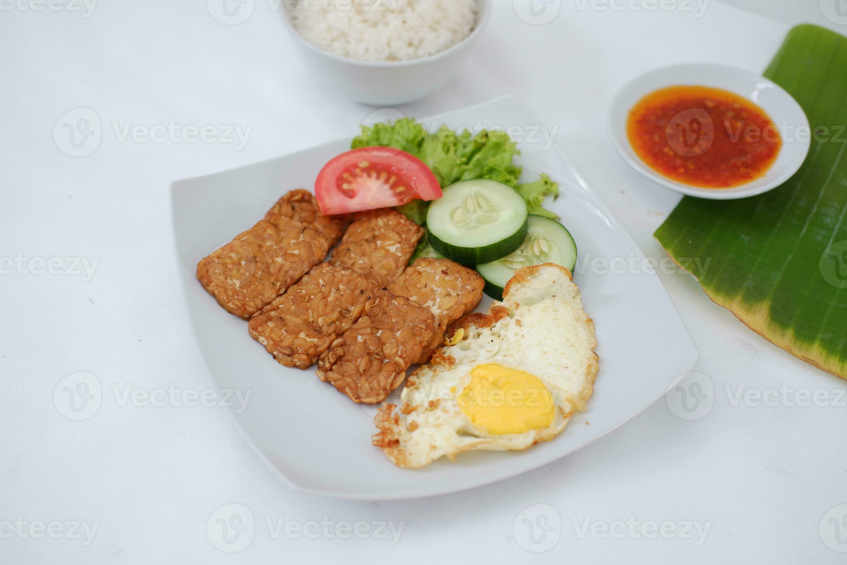 Fried tempeh cutlet with rice and fried egg on white plate 27800052