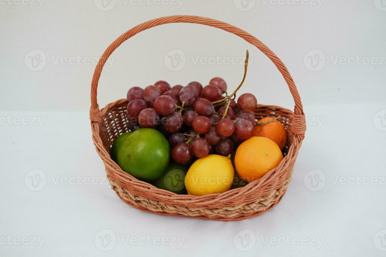 Fruits in a basket on a white background. Orange, grape, lemon. photo