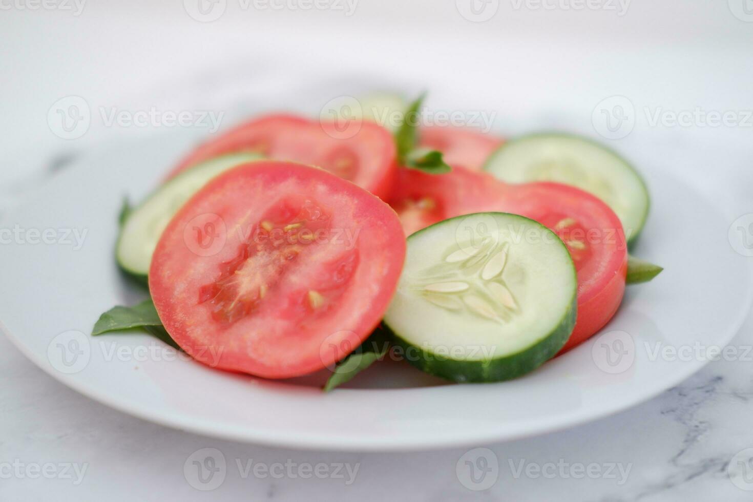 Cucumber and tomato slices on a plate on a white background photo