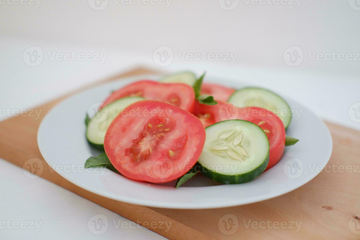 Cucumber and tomato slices on a plate on a white background photo