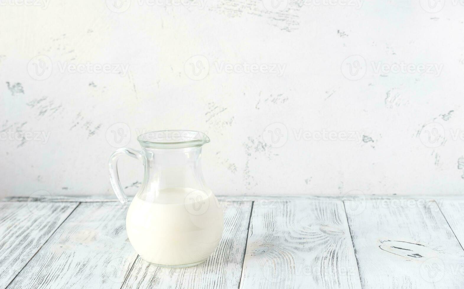 Jug of milk on the wooden background photo