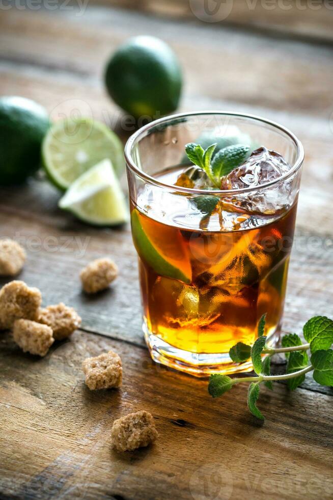 Glass of rum on the wooden background photo