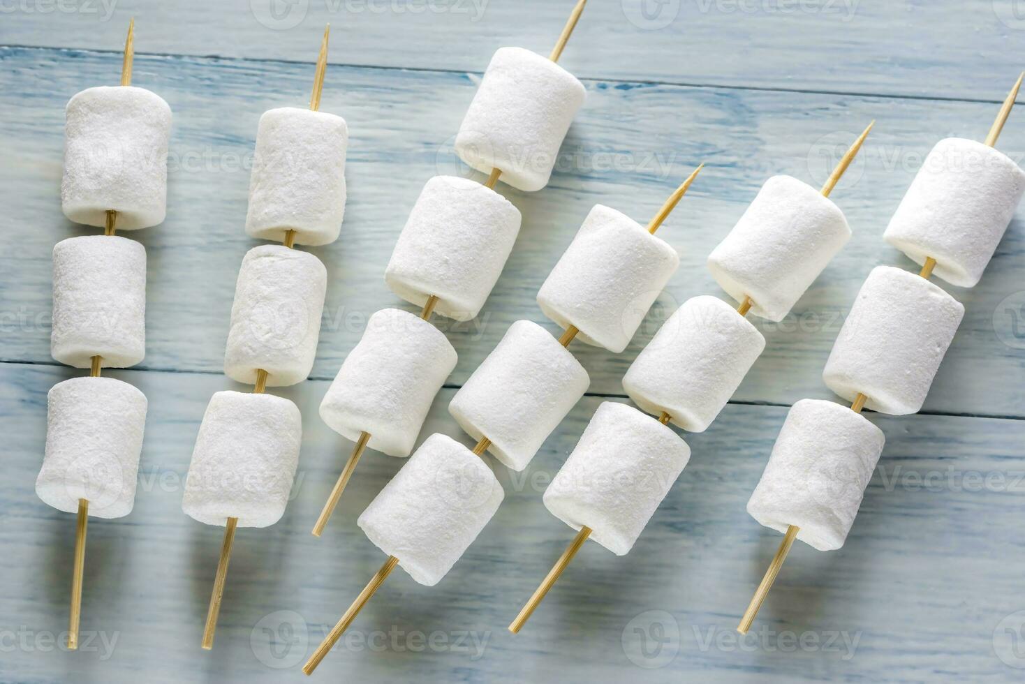 Marshmallow skewers on the wooden background photo