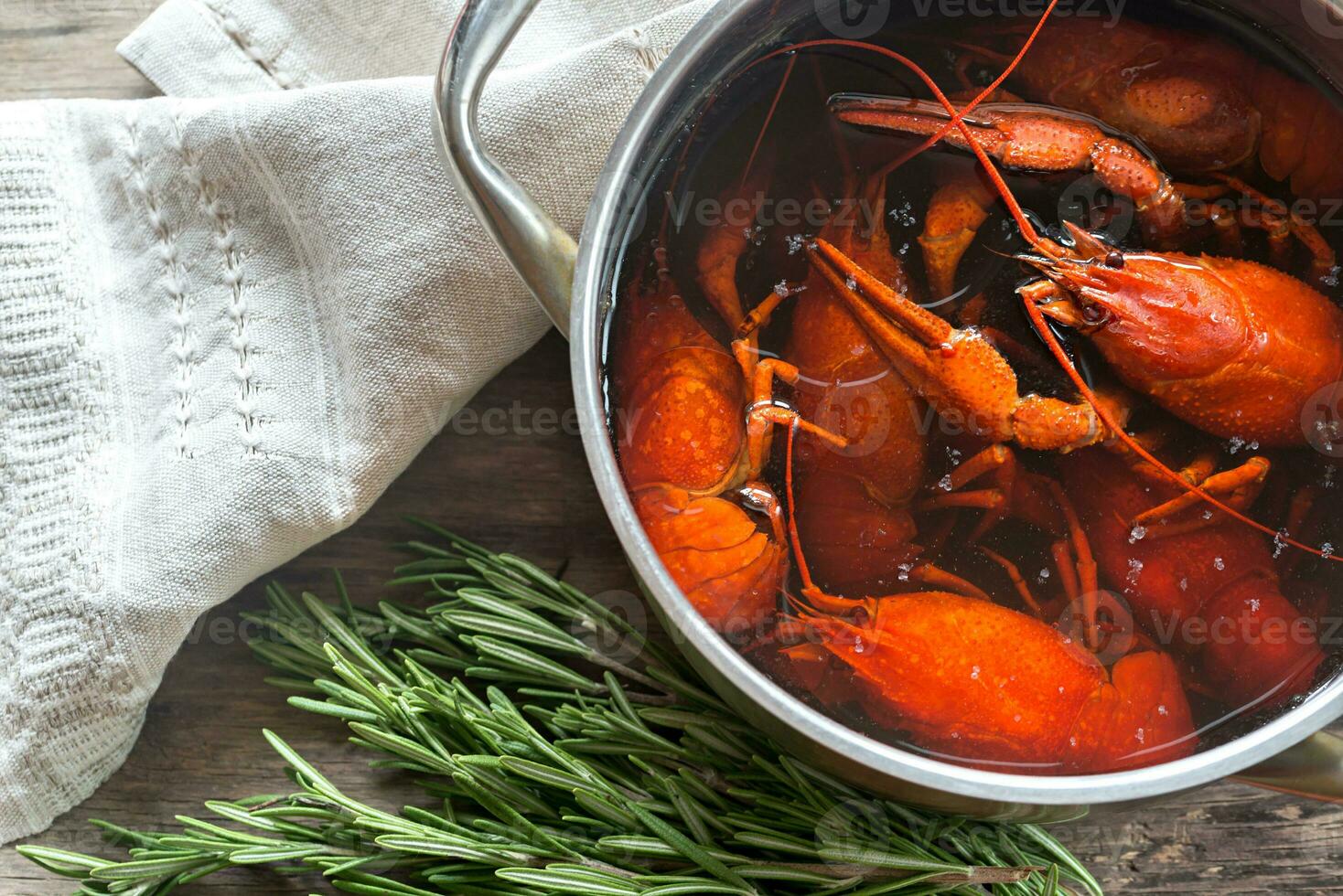 Pot with boiled crayfish on the wooden table photo