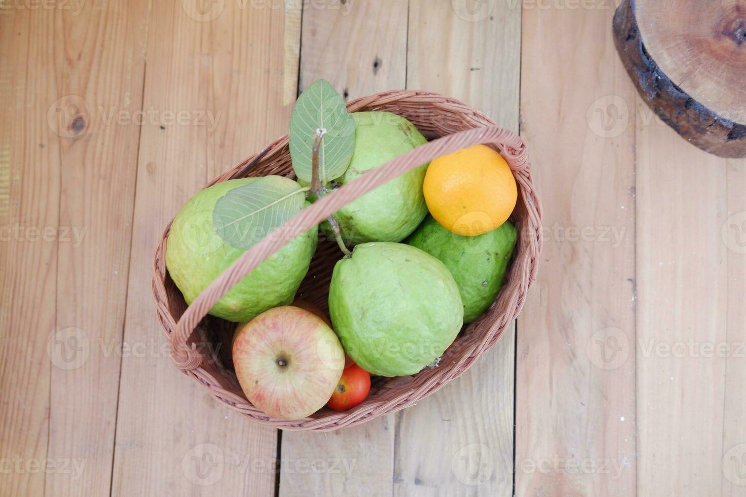 Basket of apples, oranges and guava on a wooden table, stock photo
