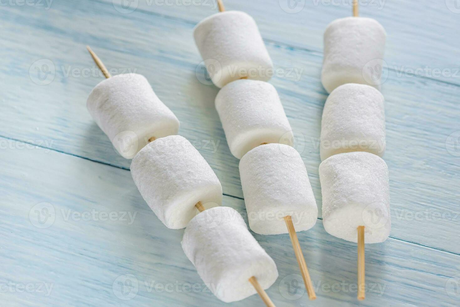 Marshmallow skewers on the wooden background photo