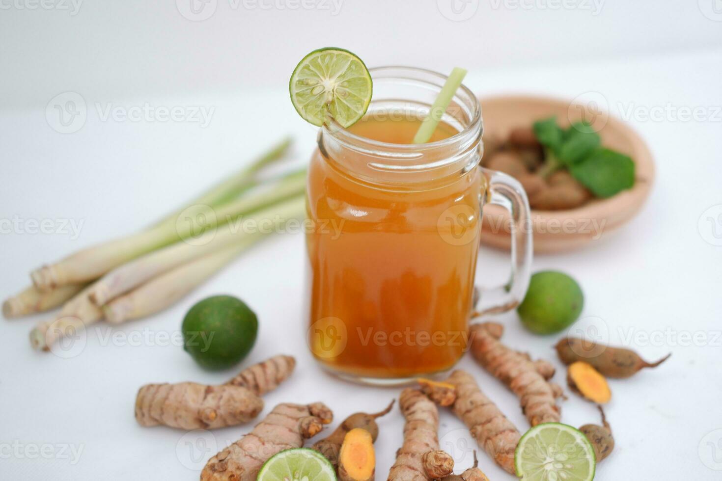 Fresh ginger and lemon juice in a glass jar with ginger roots on white background. photo