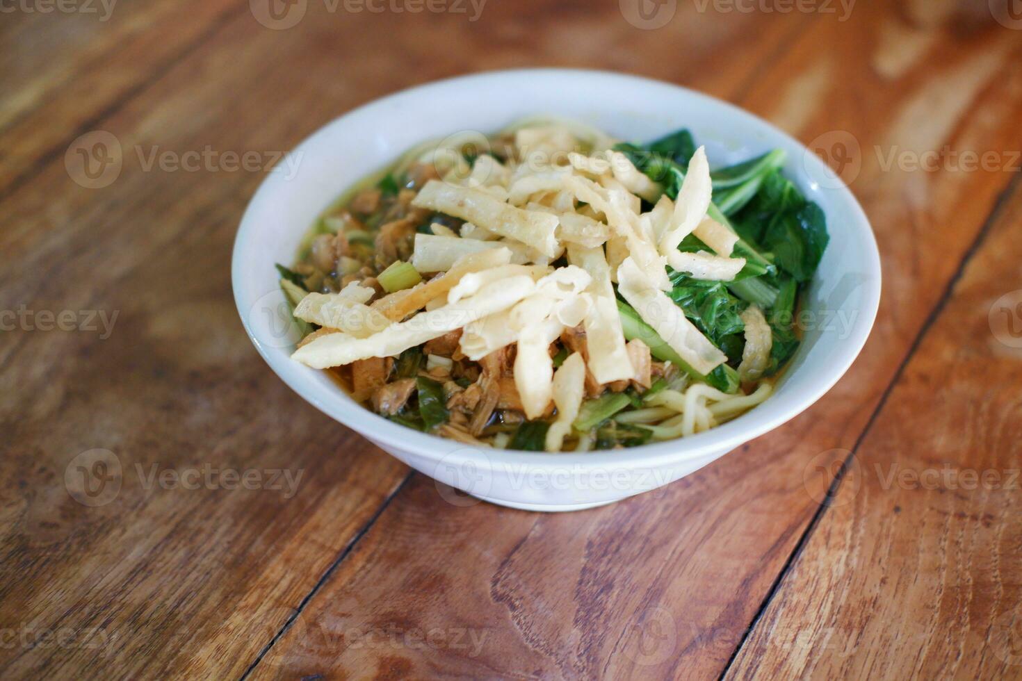 Fried noodle in white bowl on wooden table photo