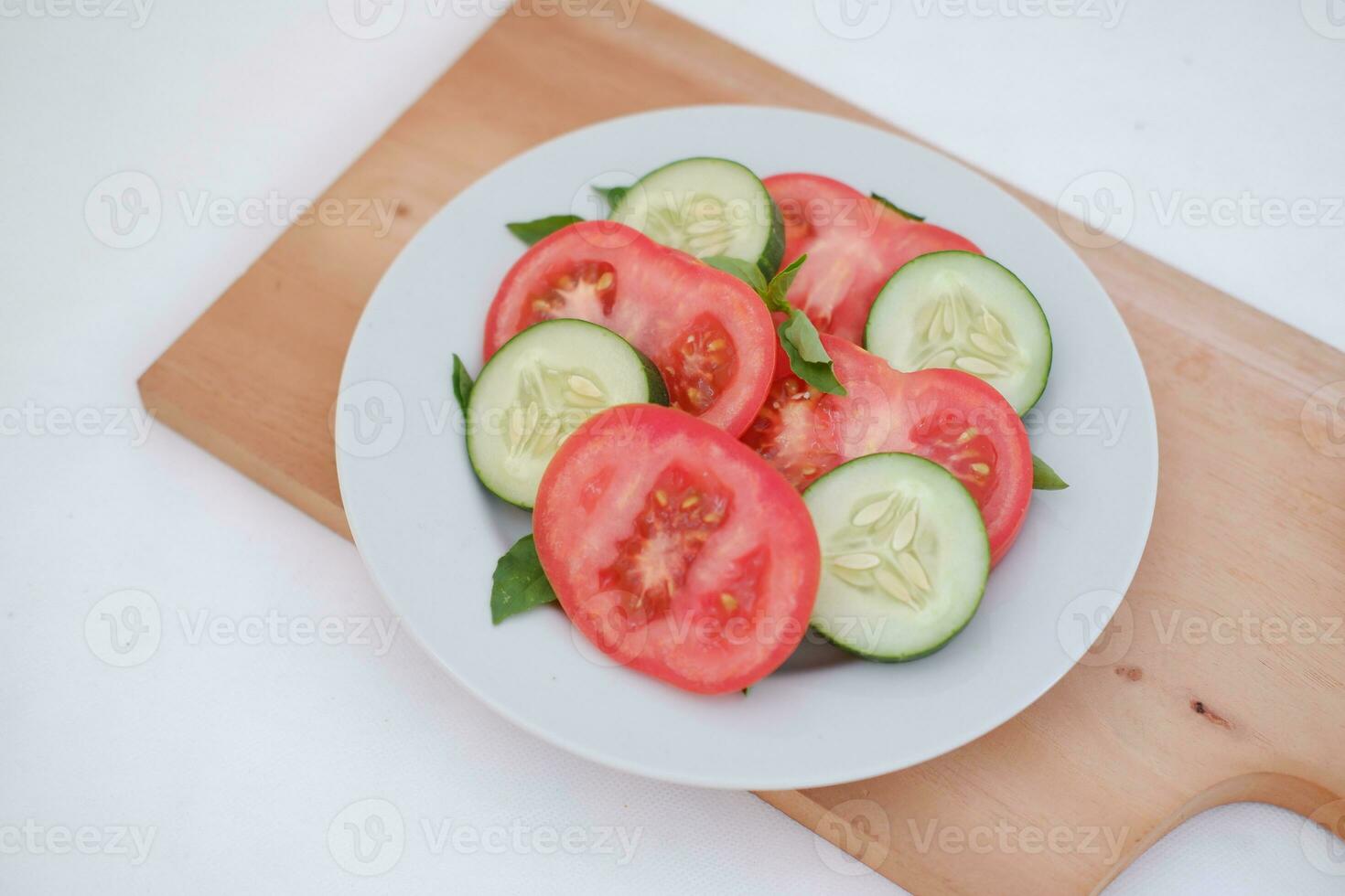 Cucumber and tomato slices on a plate on a white background photo