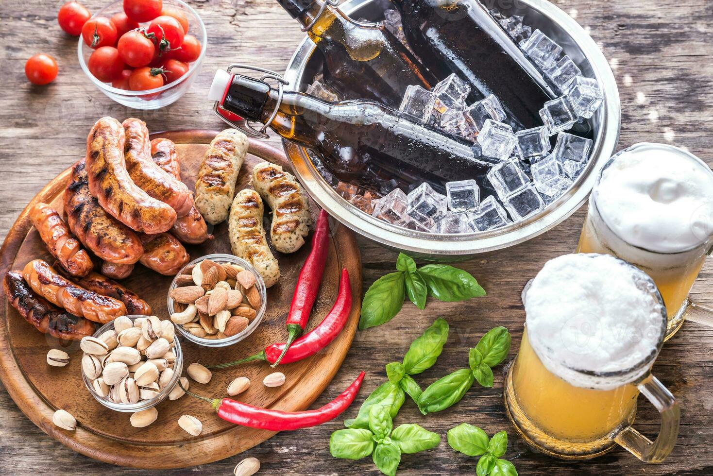 Grilled sausages with appetizers and mugs of beer photo