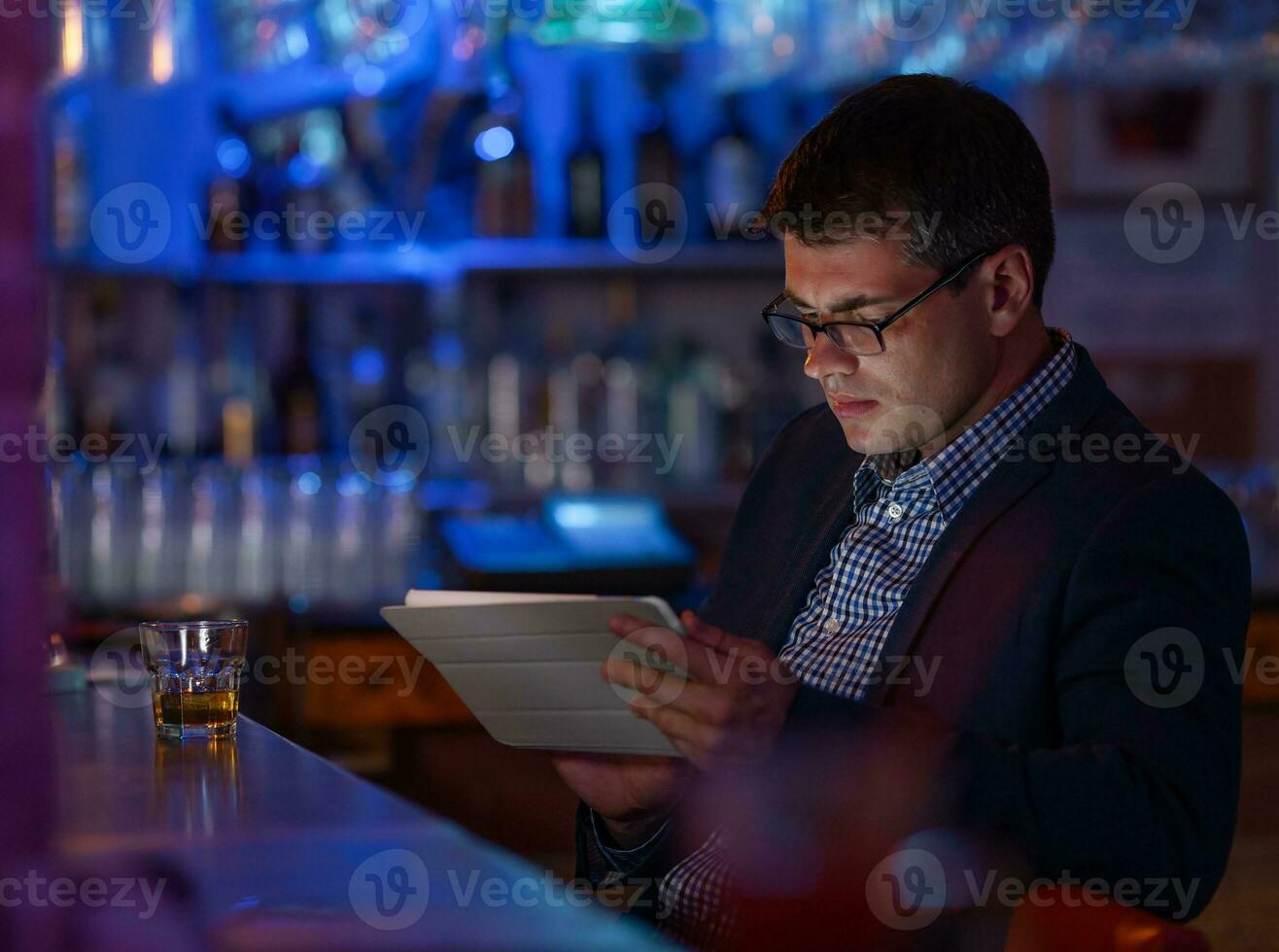 empresario con tableta ordenador personal y whisky a el bar mostrador foto