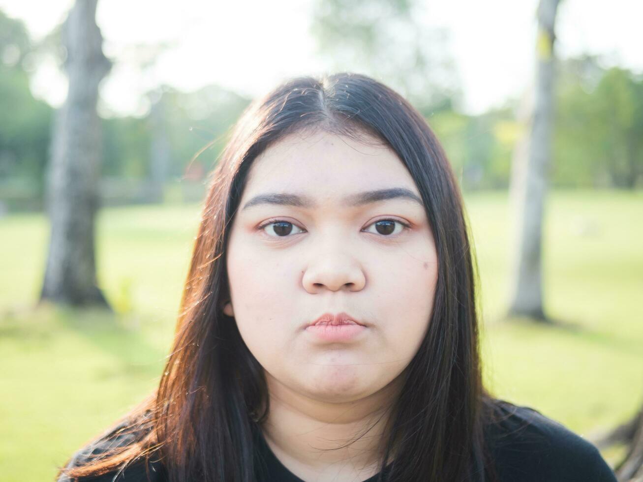 retrato joven mujer niña asiático gordito linda hermosa largo negro pelo uno persona vestir negro camisa mirando en jardín parque al aire libre noche luz de sol Fresco sonriente alegre contento relajarse verano día foto