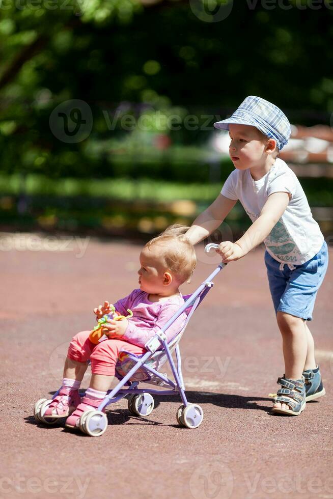 Boy pushing sister in a stroller photo
