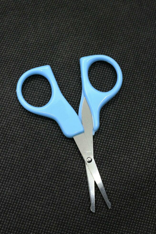 Small blue scissors on a black background photo