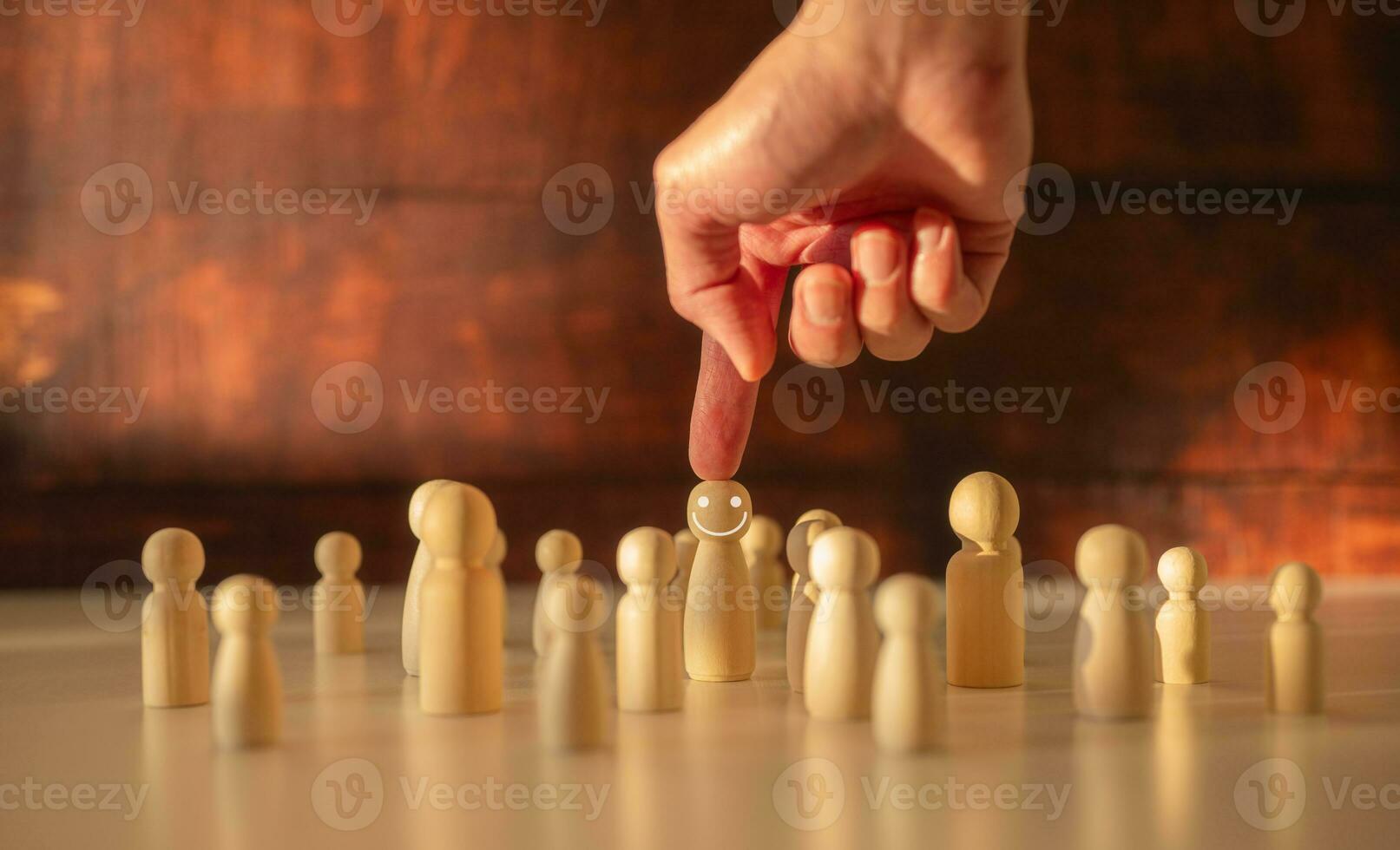 searching for team leader Hand picking up wooden people from crowd in concept of human resources for business organizations and leadership photo