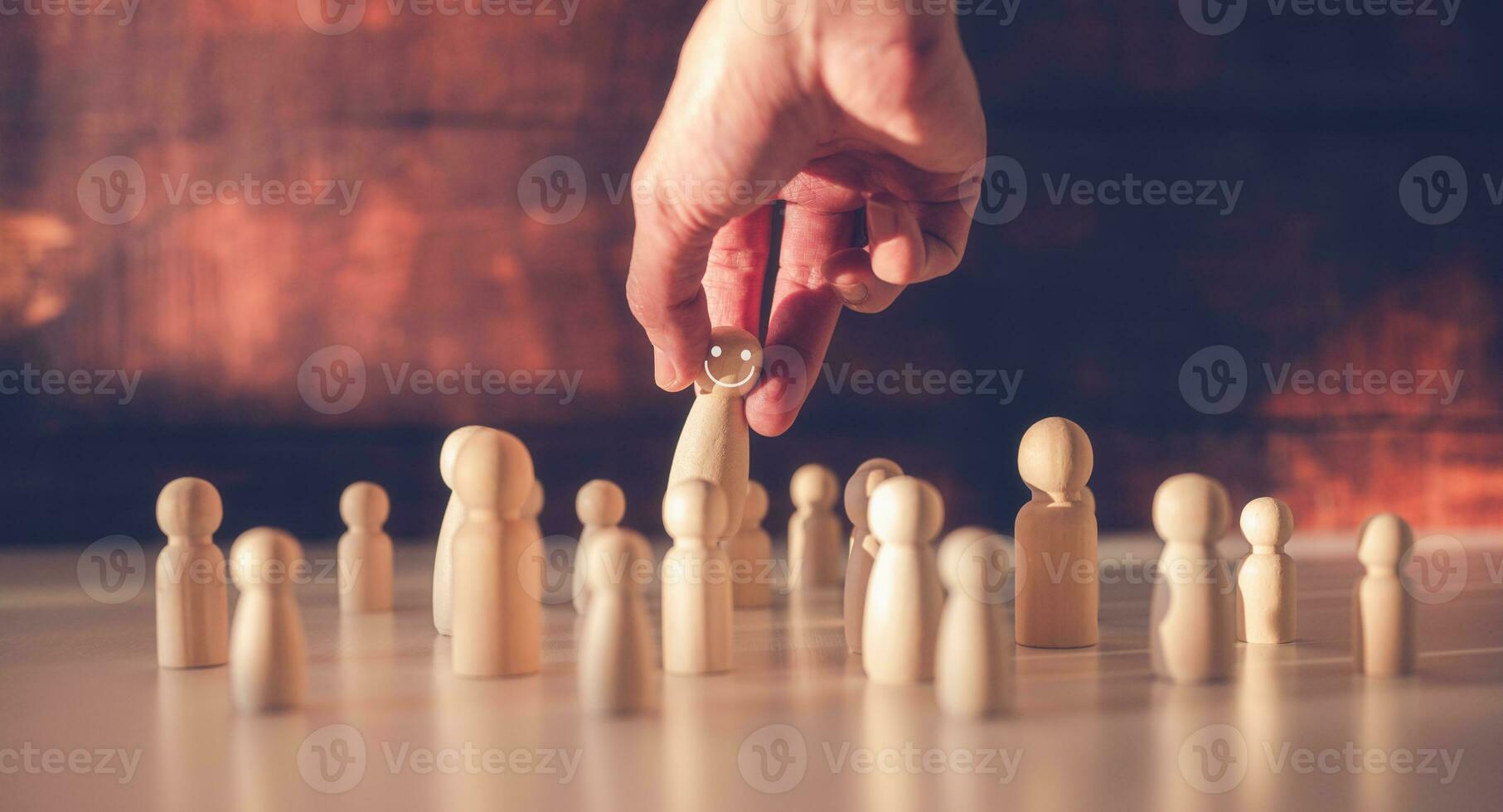 searching for team leader Hand picking up wooden people from crowd in concept of human resources for business organizations and leadership photo