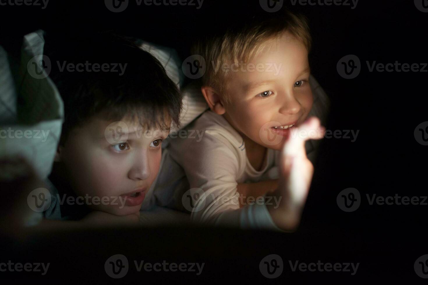 Two boys watching movie or cartoon on pad at night photo