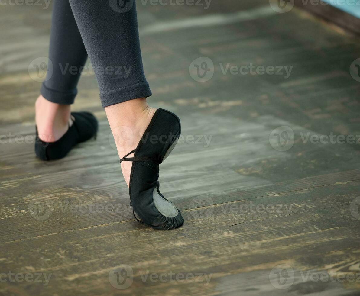 Close up view to ballerinas legs in pointes on wooden floor photo