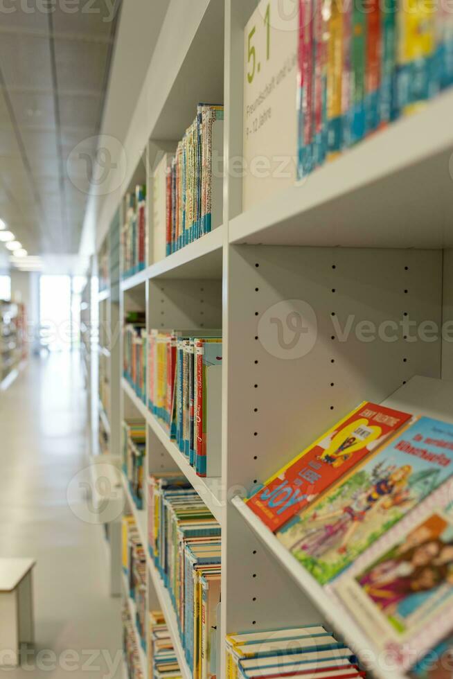 White bookshelves in the library, on which there are many books. photo