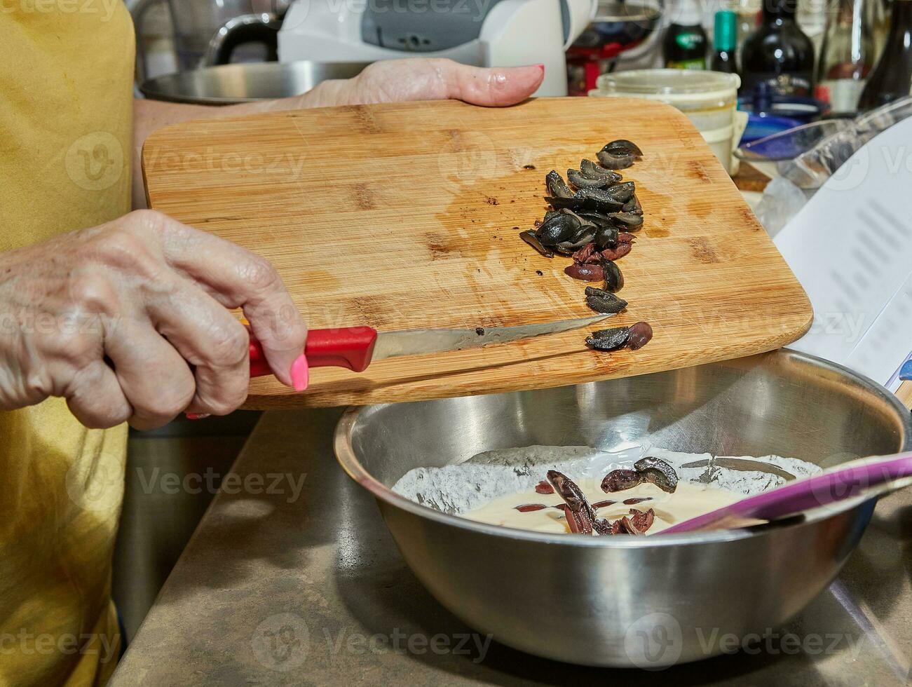 cocinero agrega aceitunas a el tarta masa en el cuenco foto