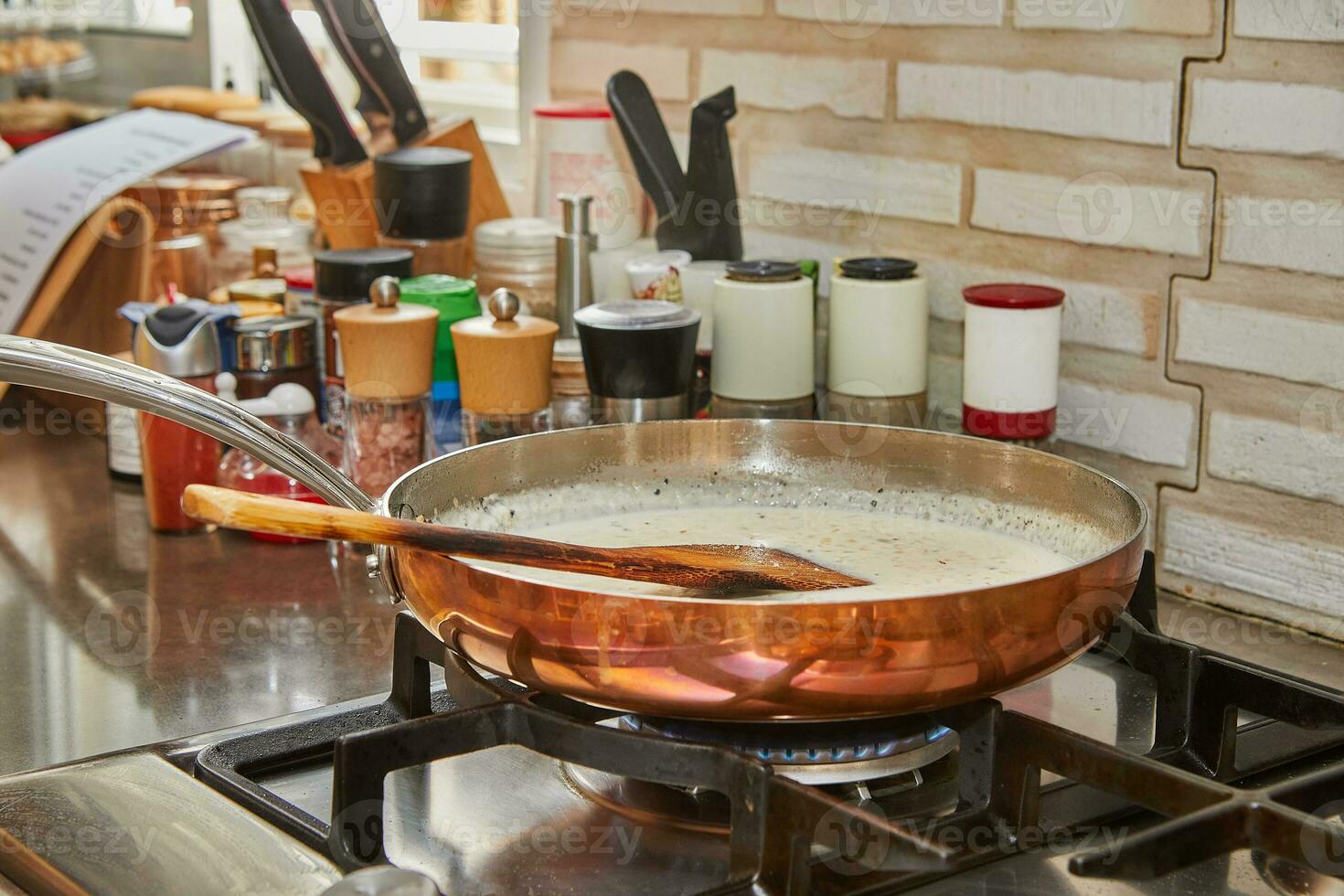 Milk and chopped onions are fried in copper saucepan over gas fire photo