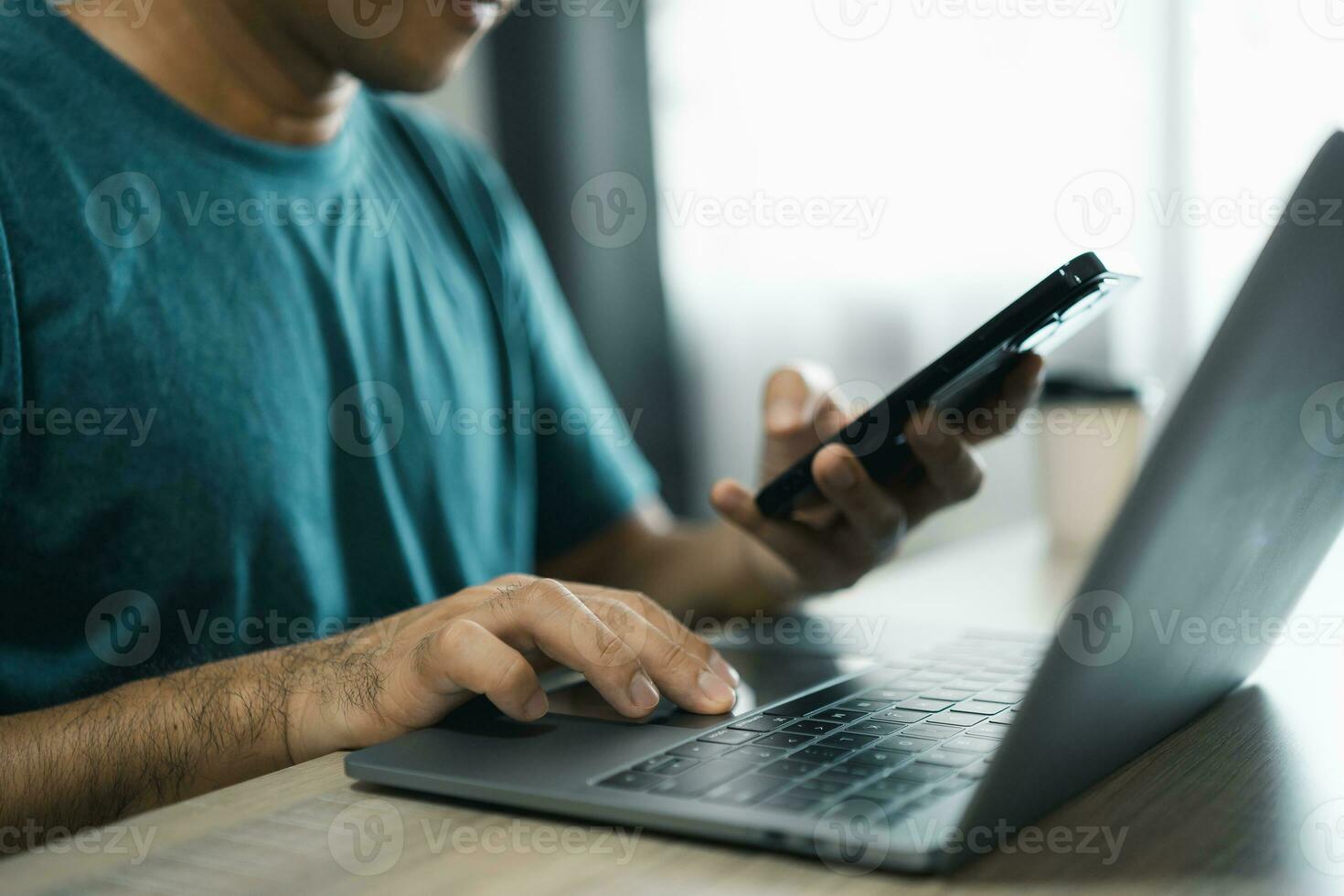 Man using smartphone after working with laptop on table, businessman using mobile phone to search or social media or shopping online. Business concept smart phone technology conversation conferrence. photo