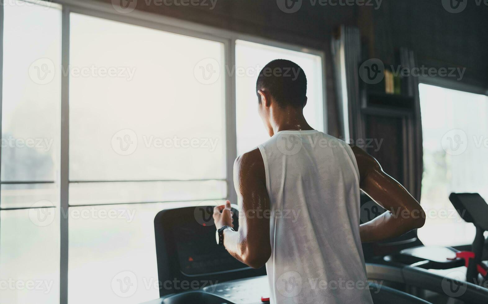 Back side of asian sportman runner running on treadmill in fitness club. Cardio workout. Healthy lifestyle, guy training in gym. Sport running concept. photo