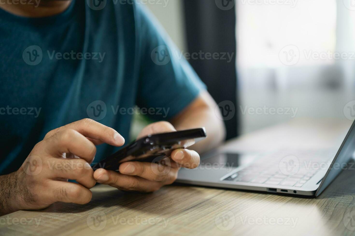 Man using smartphone after working with laptop on table, businessman using mobile phone to search or social media or shopping online. Business concept smart phone technology conversation conferrence. photo