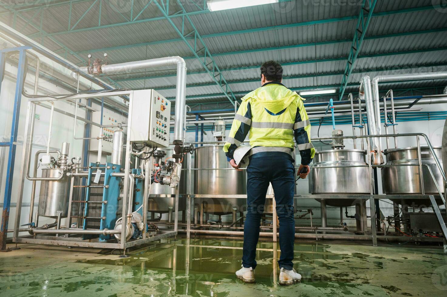 Commitment caucasian technician engineer man in safety uniform standing with pipeline, boiler tank in beverage processing laboratory plant photo