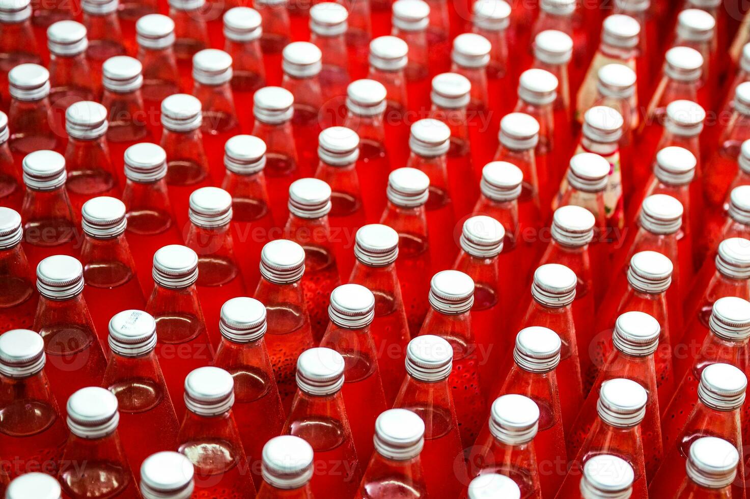 Red juice bottles with screw cap in conveyor belt at beverage processing plant photo
