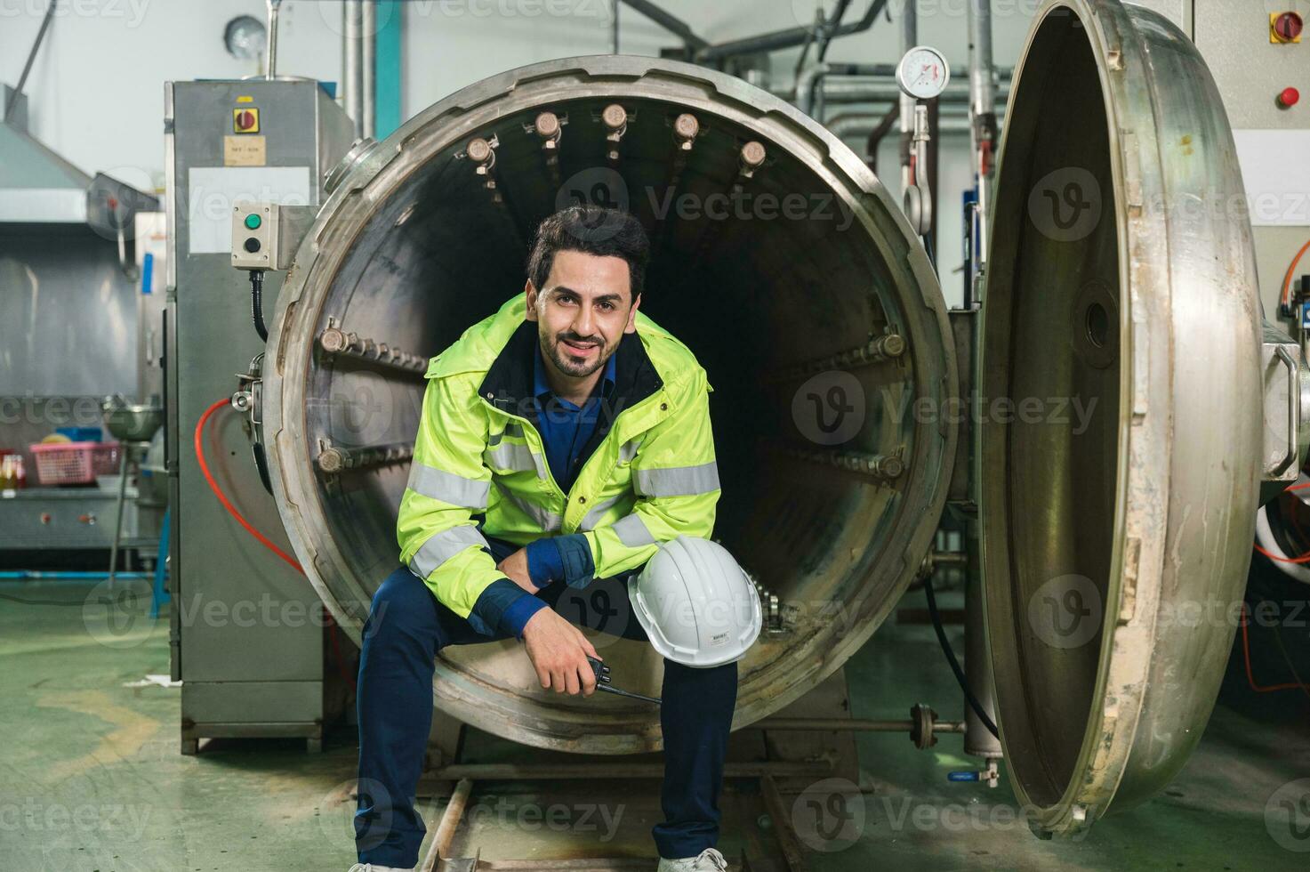 Caucasian engineer man in safety uniform sitting and reporting on processing large duct contrainer in industry manufacturing factory photo