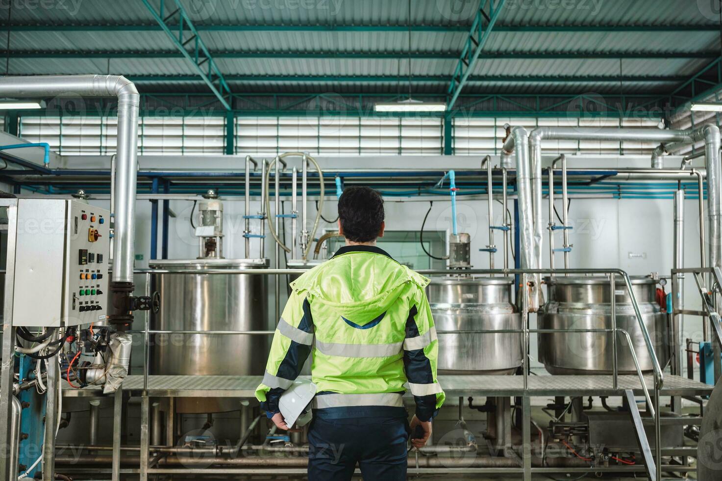 Caucasian technician engineer man in safety uniform standing with pipeline, boiler tank in beverage processing laboratory plant photo