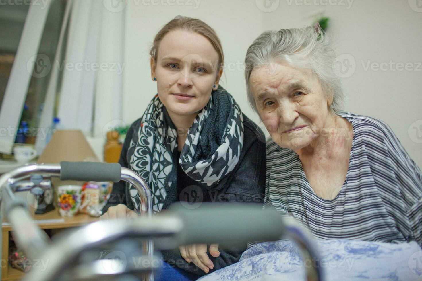 A portrait of two women, young and elderly, sitting close to each other photo