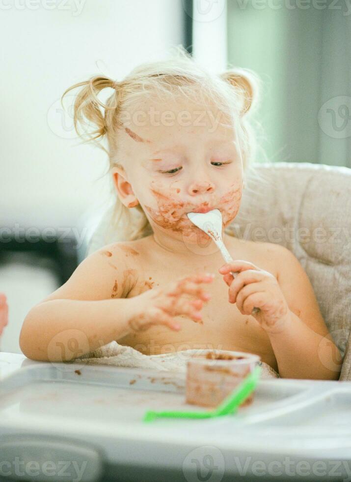 Baby with dirty face enjoying her meal photo