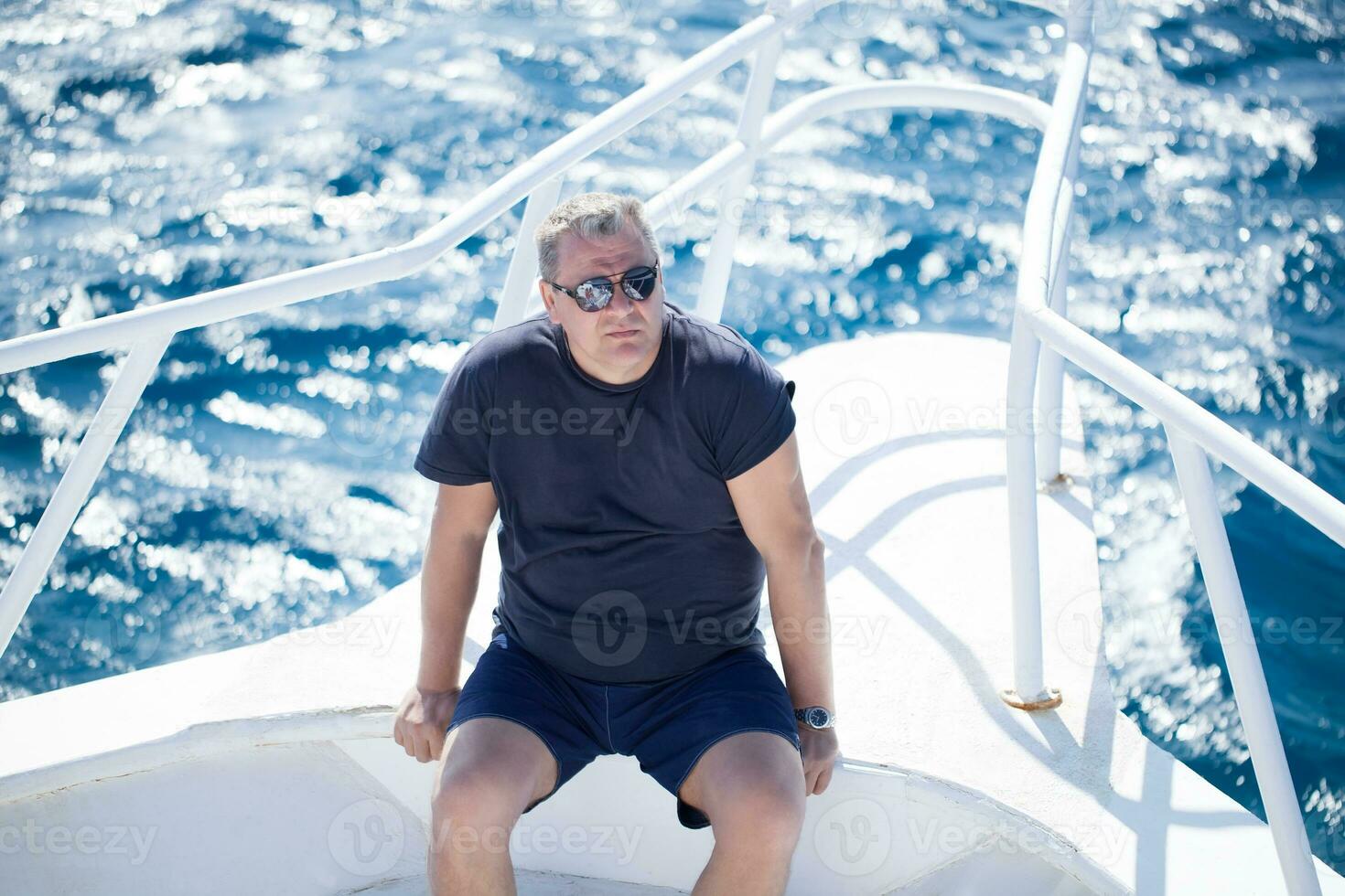 Man sitting on the prow of a boat photo