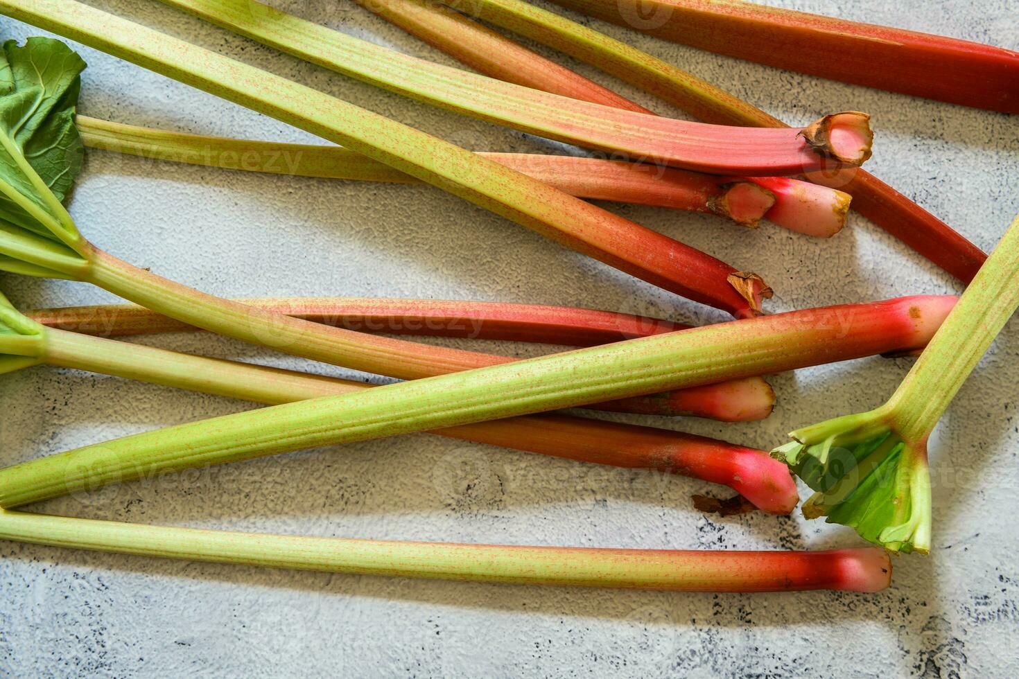 Fresh ripe green and red rhubarbs on a rustic grey and white table 2 photo