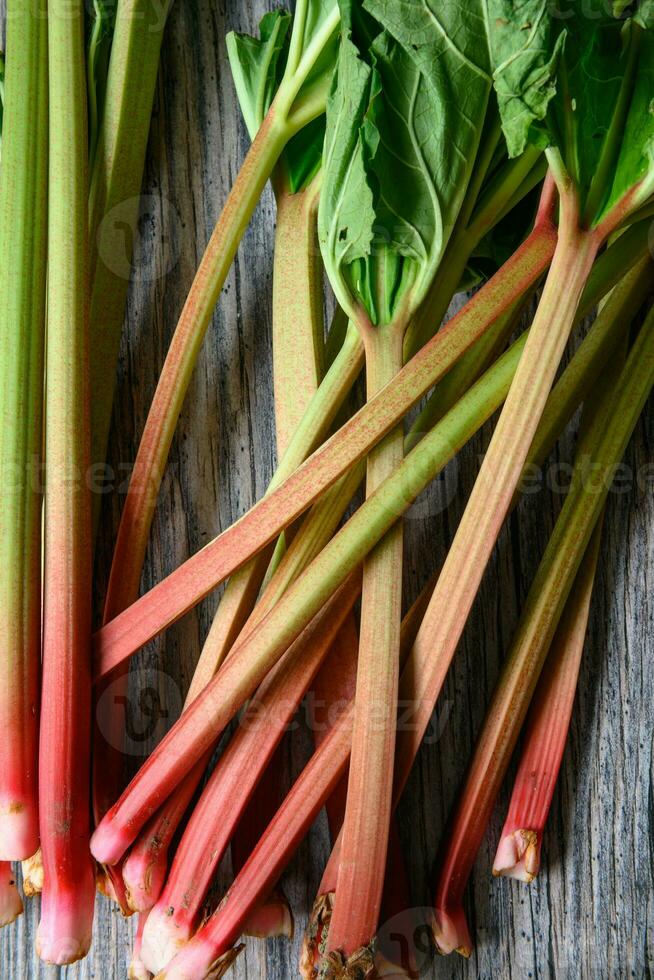 Fresh ripe green and red rhubarbs on a wood table photo