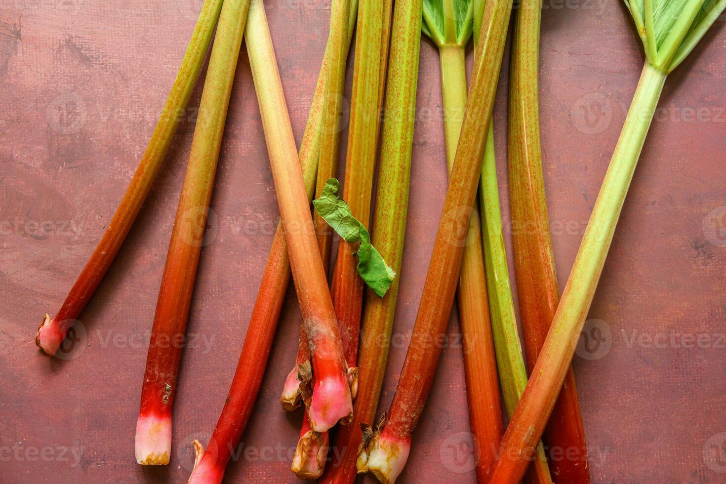 Fresh ripe green and red rhubarbs on a rustic burgundy table 2 photo