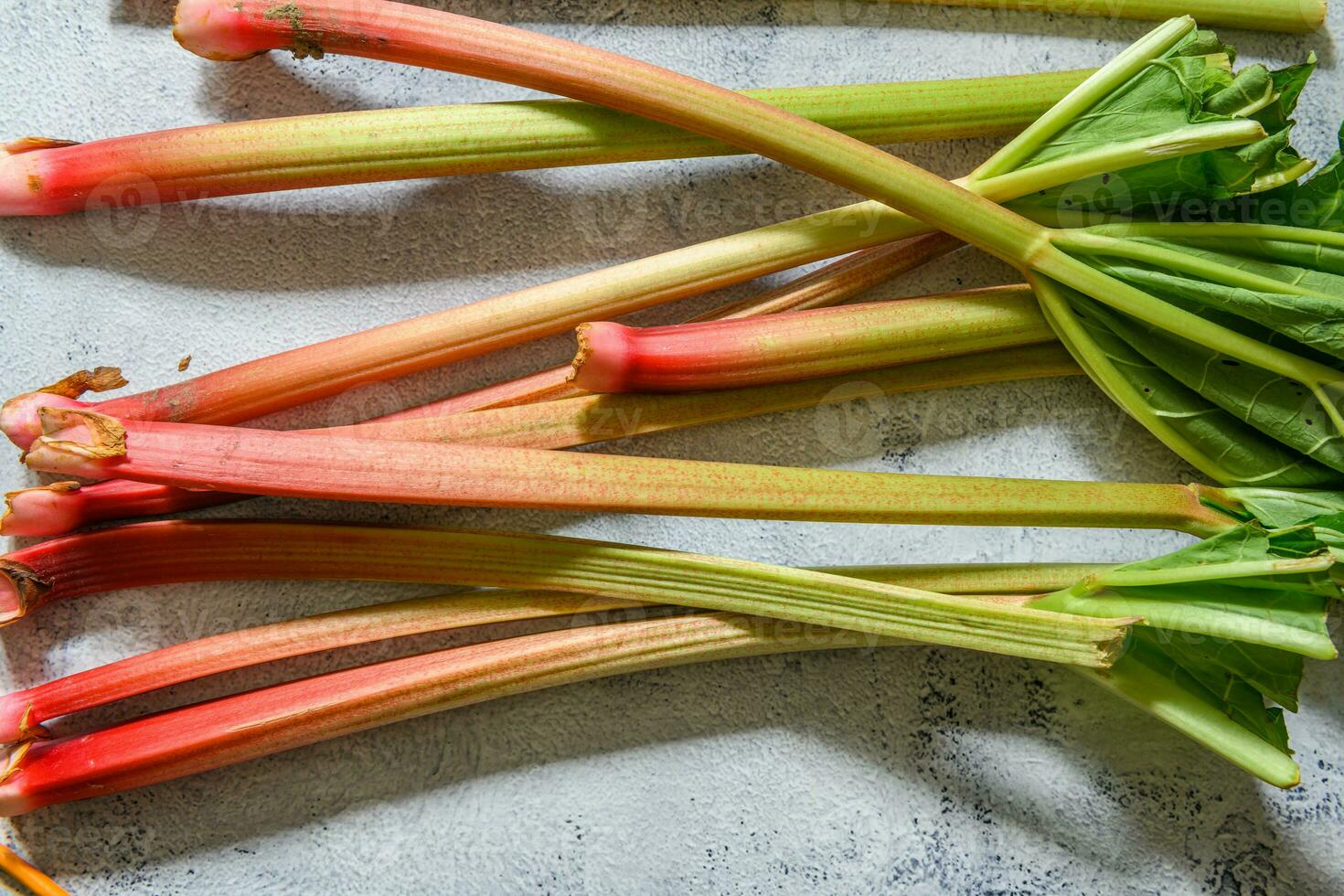 Fresh ripe green and red rhubarbs on a rustic grey and white table photo