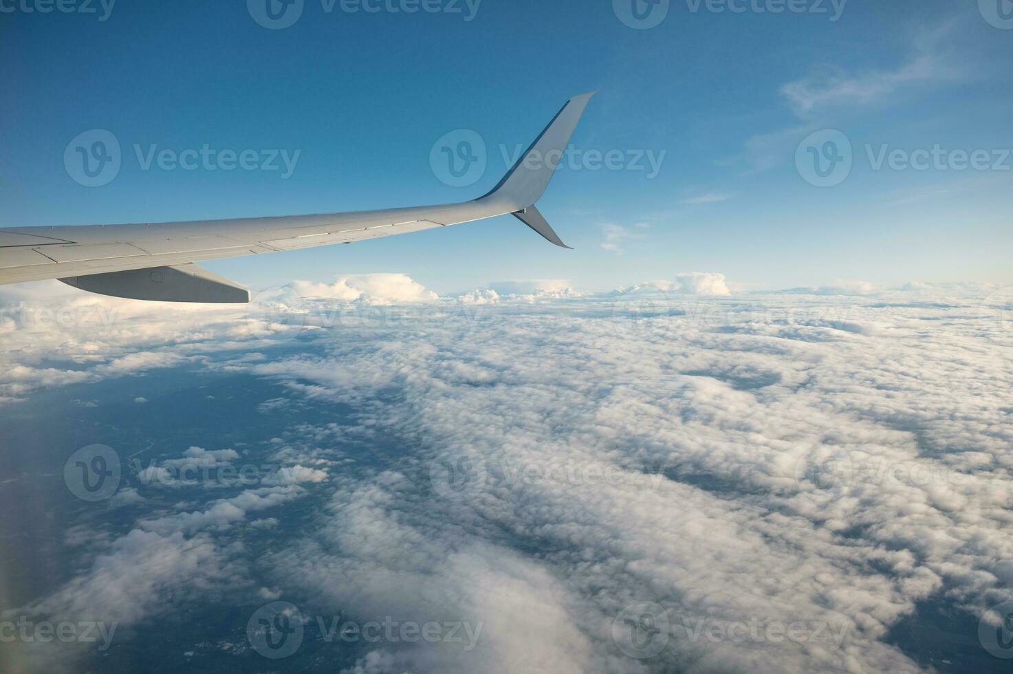 Wing of an airplane flying over white cloud in the sky during the vacation photo