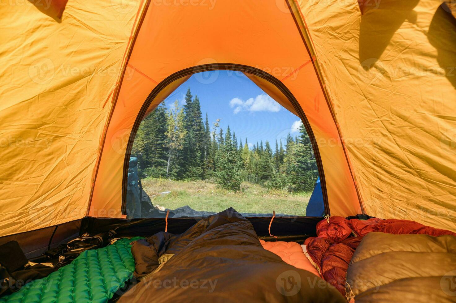 Camping with traveler stretching legs in sleeping bag on orange tent at national park photo