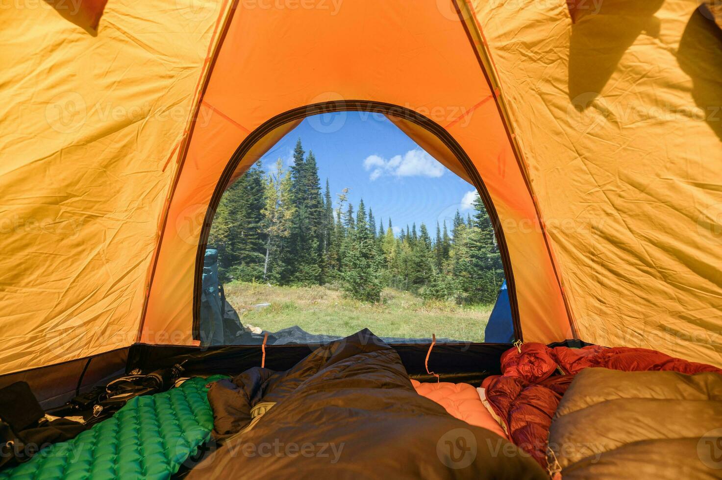 Camping with traveler stretching legs in sleeping bag on orange tent at national park photo